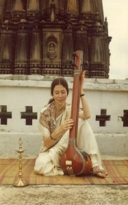 Eine Frau sitzt am Boden mit einer Sitar.